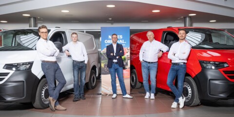 Teamfoto von Steven Klatt und seinem Nutzfahrzeug-Team ('Nutzis') im Ausstellungsraum des Autohauses Wolfsburg, flankiert von einem weißen und einem roten Kastenwagen.