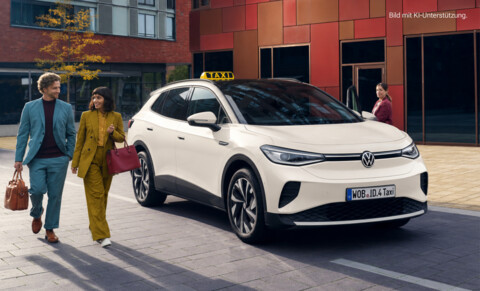 Ein weißes Volkswagen ID.4 Taxi steht vor modernen Gebäuden, während ein Mann und eine Frau in eleganter Kleidung vorbeigehen und die Fahrerin am Fahrzeug wartet.